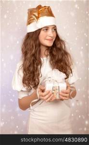 Closeup portrait of cute little Santa helper looking on a side, sweet teen girl with white wrapping gift box on pink snowing background