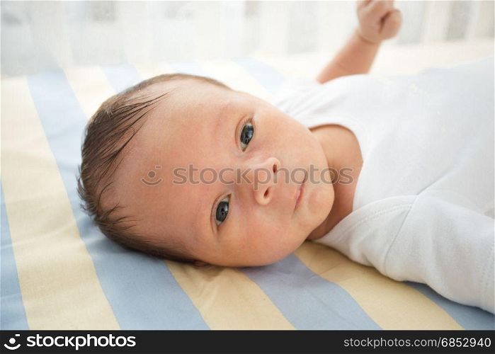 Closeup portrait of cute newborn baby lying in bed