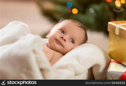 Closeup portrait of cute newborn baby lying under beige blanket