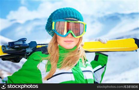 Closeup portrait of cute ski trainer, active woman wearing sportive goggles and holding in hands ski, active winter vacation, happiness and enjoyment concept