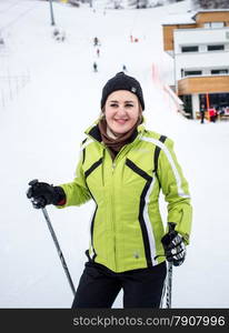 Closeup portrait of cute smiling female skier on downhill of ski slope