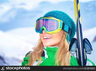 Closeup portrait of cute smiling skier girl wearing sportive goggles and holding in hands ski, active winter vacation, happiness and enjoyment concept
