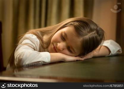 Closeup portrait of cute tired schoolgirl sleeping on desk