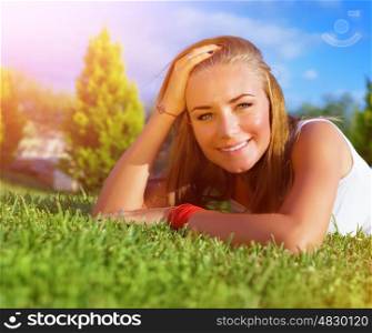 Closeup portrait of cute woman lying down on green grass field, relaxation outdoors, summer holidays, carefree lifestyle, vacation concept