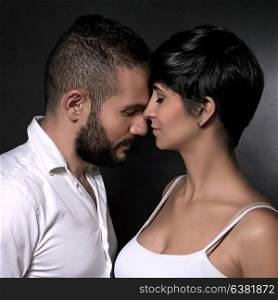 Closeup portrait of gentle loving couple over black background, enjoying each other, romantic relationship, affection and tenderness concept