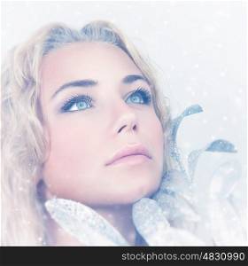 Closeup portrait of gorgeous female with beautiful makeup holding decorative shiny leaves over snowy background, stylish look for Christmas