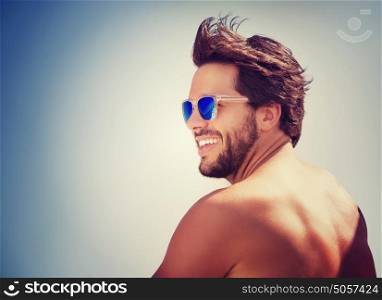 Closeup portrait of handsome cheerful man over blue sky background, happy guy having fun on the beach, enjoying summer holidays