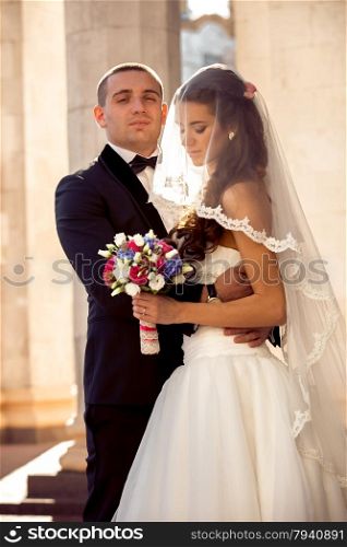 Closeup portrait of handsome groom hugging beautiful bride on street at sunny day