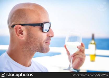 Closeup portrait of handsome man drinking wine in outdoors restaurant on luxury yacht, tasting luxury alcohol beverage