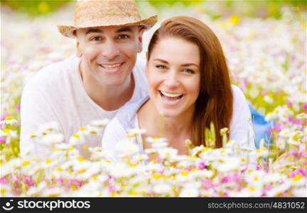 Closeup portrait of happy couple lying down on fresh daisy field, romantic date, summer vacation, love concept