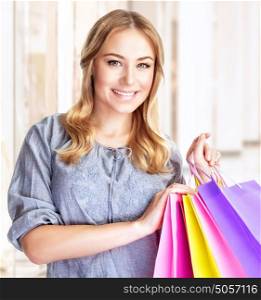 Closeup portrait of happy customer with colourful paper bag in great mall, attractive girl enjoying shopping, buying gifts, spending money concept