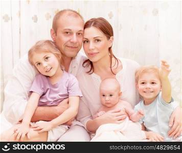 Closeup portrait of happy family at home, young parents spending time with adorable children, relaxed together, love and happiness concept
