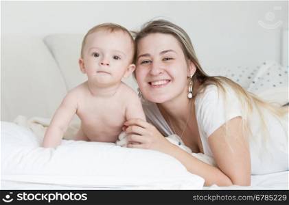 Closeup portrait of happy smiling baby boy and mother lying on pillow and looking at camera
