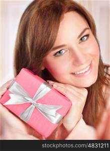 Closeup portrait of happy smiling woman holding in hands present wrapped in pink paper with silver ribbon, receive gift in Valentine day