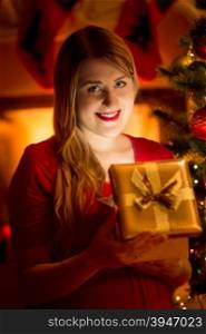 Closeup portrait of happy woman holding glowing Christmas gift box