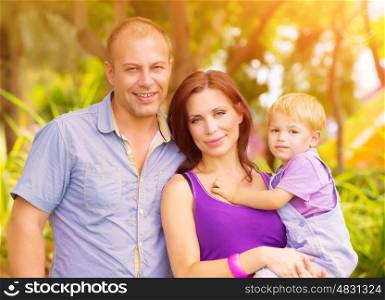 Closeup portrait of happy young family having fun outdoors, cheerful parents with adorable kid walking in the park, summer vacation