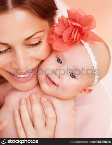 Closeup portrait of happy young mother hugging sweet little newborn daughter, cute baby girl wearing red floral head decoration, love concept