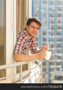 Closeup portrait of hipster guy drinking coffee on balcony