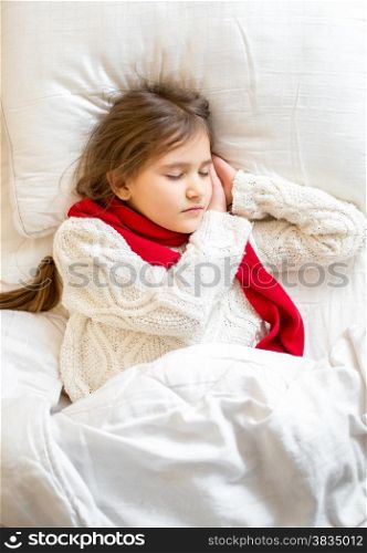 Closeup portrait of little girl in sweater sleeping at bed