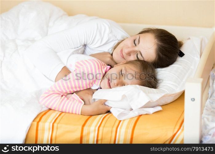 Closeup portrait of little girl sleeping with mother on bed