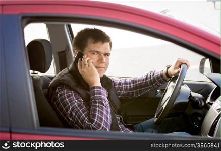 Closeup portrait of male driver talking by phone while driving a car