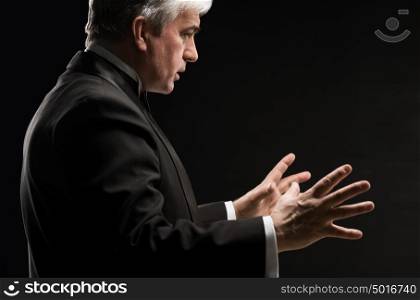 Closeup portrait of male orchestra conductor directing with his hands in concert. Business leading concept