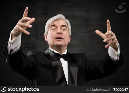 Closeup portrait of male orchestra conductor directing with his hands in concert. Business leading concept
