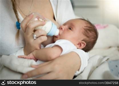 Closeup portrait of mother feeding newborn baby from bottle