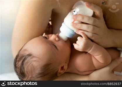 Closeup portrait of mother feeding newborn baby from bottle