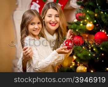 Closeup portrait of mother with daughter decorating Christmas tree
