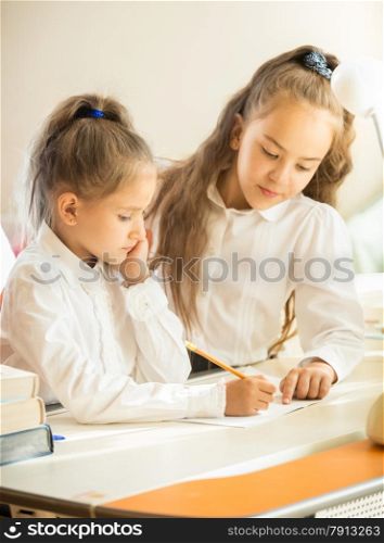 Closeup portrait of older sister helping with homework to younger one