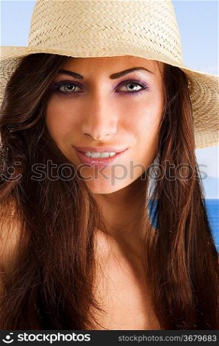 closeup portrait of pretty brunette woman wearing a nice summer hat with long hair
