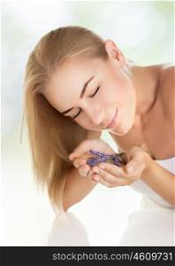 Closeup portrait of pretty girl enjoying gentle aroma of lavender flowers, closing eyes of pleasure, healthy lifestyle, body care, spending time in a spa salon