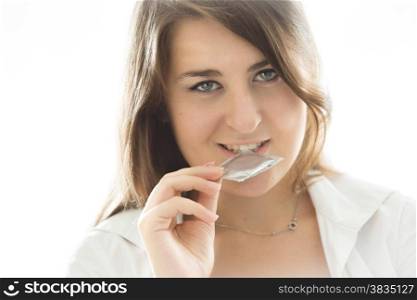 Closeup portrait of sexy brunette woman holding condom at mouth
