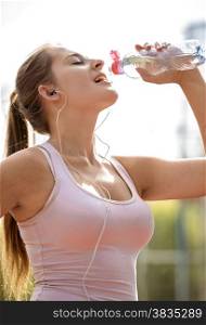 Closeup portrait of sexy slim woman with ponytail drinking water during jogging