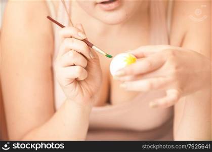Closeup portrait of sexy woman painting white easter egg