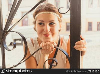 Closeup portrait of smiling girl leaning at forged gates
