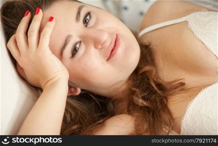 Closeup portrait of smiling woman in bra lying in bed