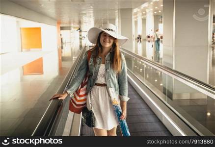 Closeup portrait of smiling woman wearing hat in airport at escalator