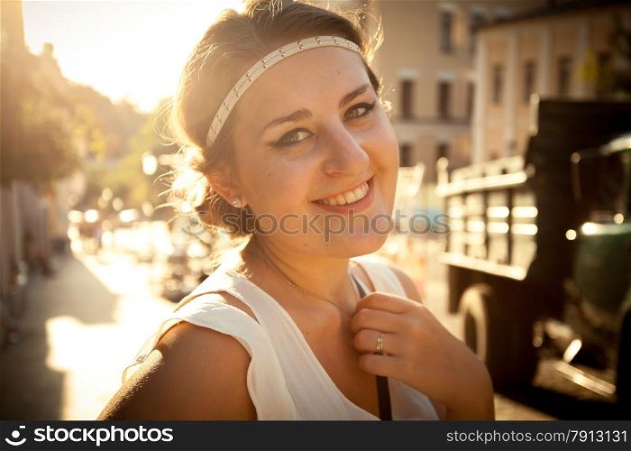 Closeup portrait of smiling woman with greek styled haircut on street at sun light