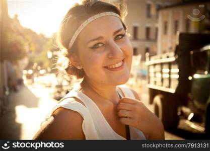 Closeup portrait of smiling woman with greek styled haircut on street at sun light