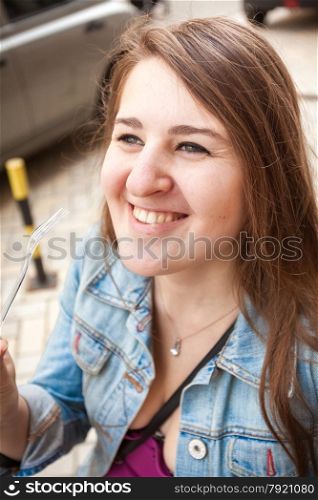 Closeup portrait of smiling young woman holding plastic fork