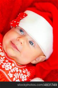 Closeup portrait of sweet little baby girl wearing red festive dress and Santa hat, having fun on Christmas party, wintertime holidays