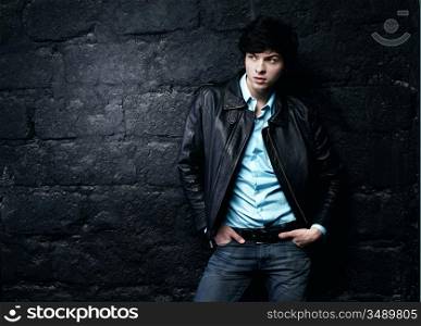 Closeup portrait of the beautiful young sexual man in a leather jacket, on a black background