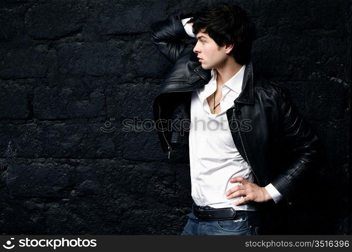 Closeup portrait of the beautiful young sexual man in a leather jacket, on a black background