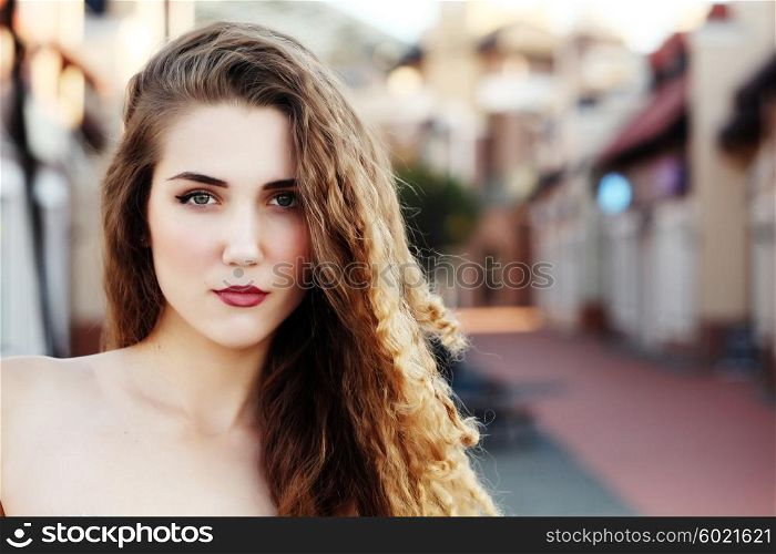 Closeup portrait of the face belong to beautiful young sexy blonde girl with curly hair pure snow white skin and bright makeup red lips, red lipstick outdoor on the street