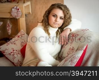 Closeup portrait of thoughtful curly woman posing on sofa at living room