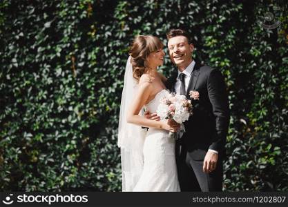 Closeup Portrait of wedding bride and groom with bouquet posing. Bridal couple, Happy Newlywed woman and man hugging. Bride and groom