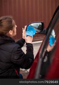 Closeup portrait of woman cleaning car mirror