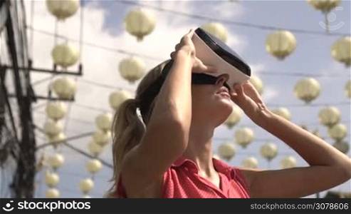 Closeup portrait of woman having fun with virtual reality glasses over chinese lamps and beautiful summer sky tree - video in slow motion